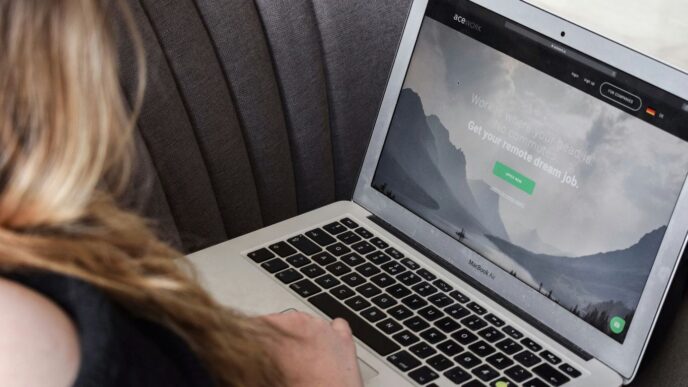 person using macbook air on gray couch