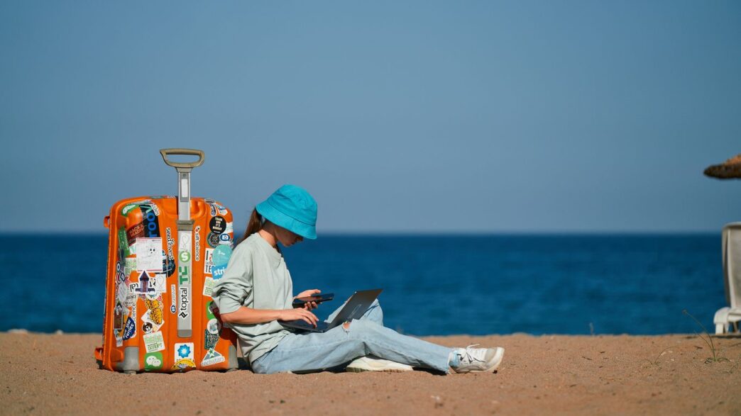 a person sitting on the beach with a suitcase