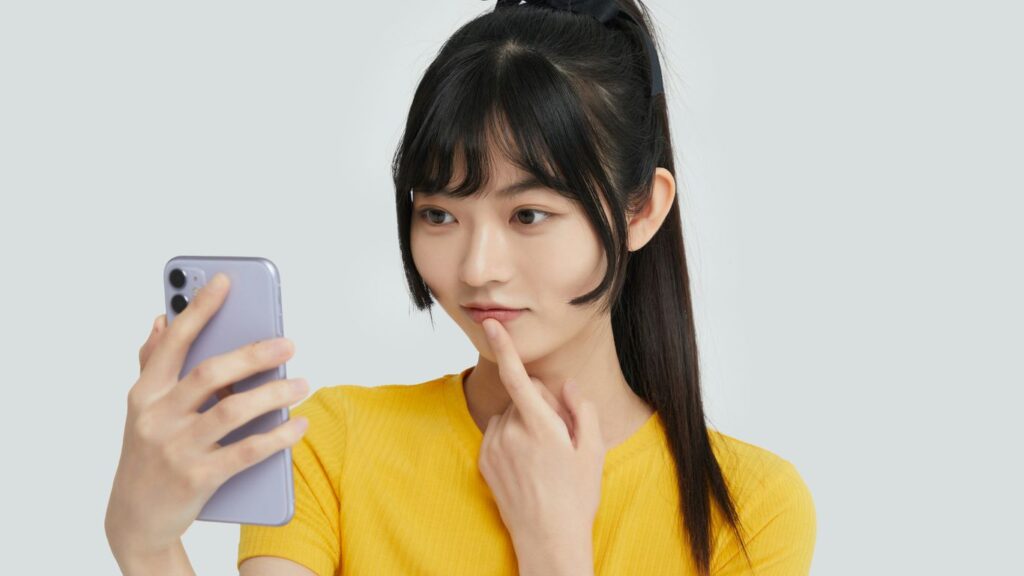 a woman in a yellow shirt holding a cell phone