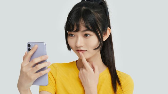 a woman in a yellow shirt holding a cell phone