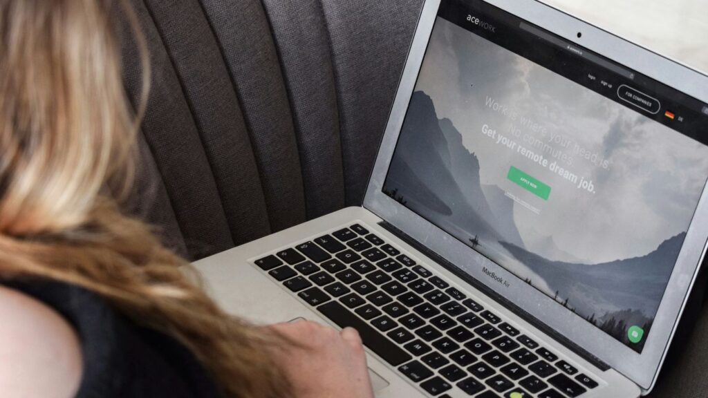 person using macbook air on gray couch