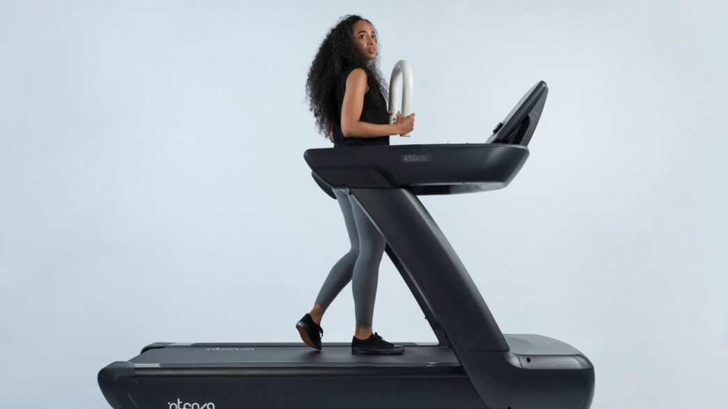 a woman is walking on a treadmill