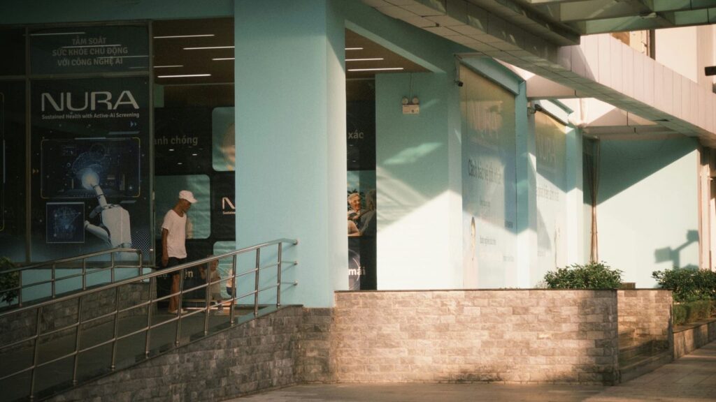 People walk past a building with a nura sign.