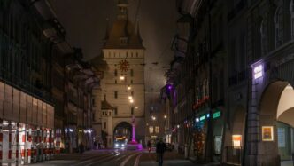 Illuminated street and clock tower at night.