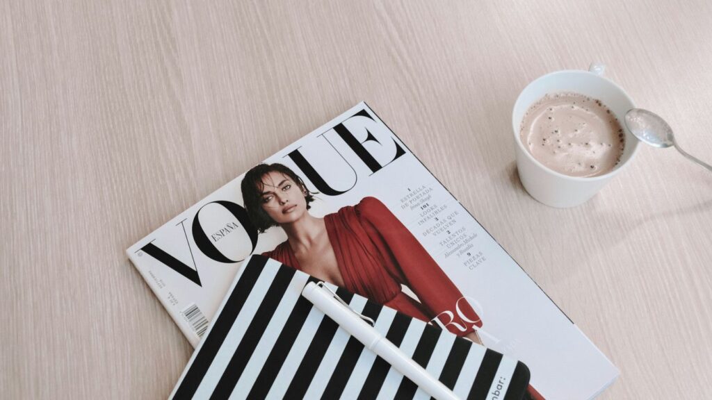 white capped pen on top of Vogue magazine beside cup of coffee