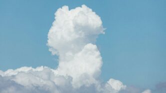 A plane flying through a cloud filled sky