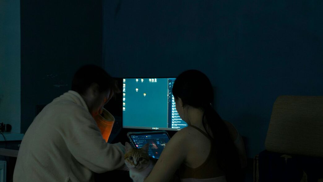 A man and a woman standing in front of a computer screen