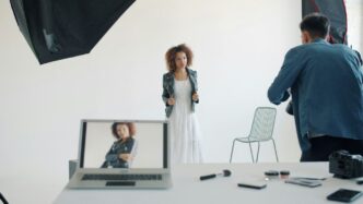 Model posing in studio with photographer and equipment
