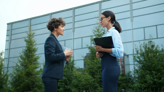 Two businesswomen talking outside modern building