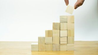 A person placing a piece of wood into a pyramid
