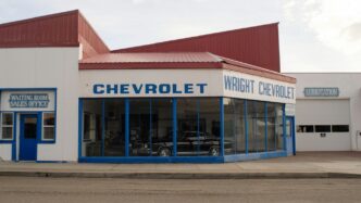 A chevrolet dealership with a car parked in front of it