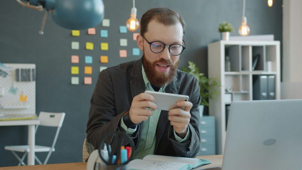 Man playing game on smartphone at desk