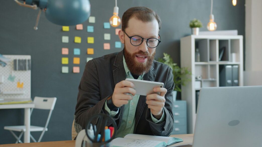 Man playing game on smartphone at desk