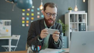 Man playing game on smartphone at desk