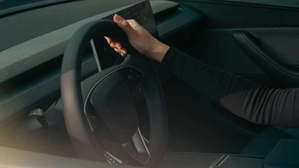 Person's hands on a car steering wheel.