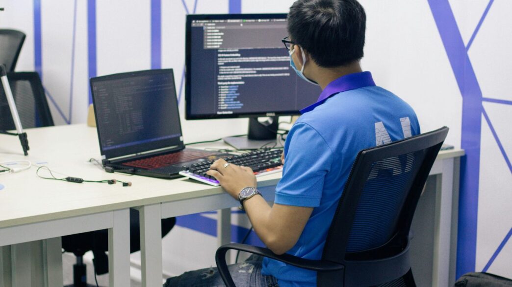 boy in blue t-shirt sitting on black office rolling chair in front of computer