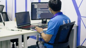 boy in blue t-shirt sitting on black office rolling chair in front of computer