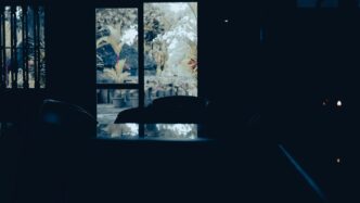 A dark room looking out at trees.