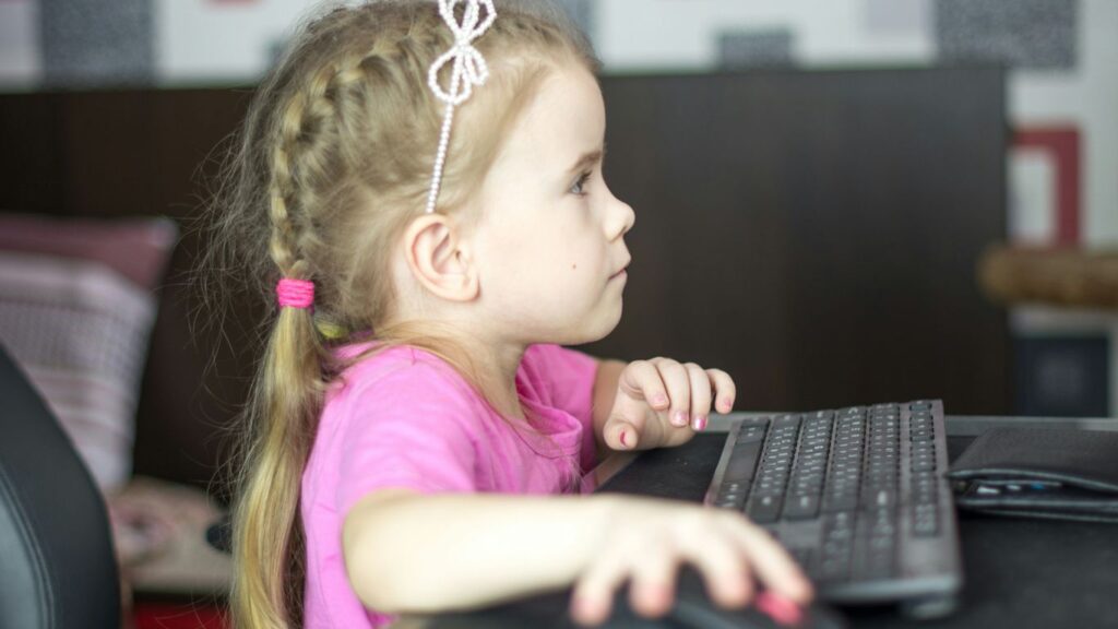 a little girl sitting in front of a computer keyboard