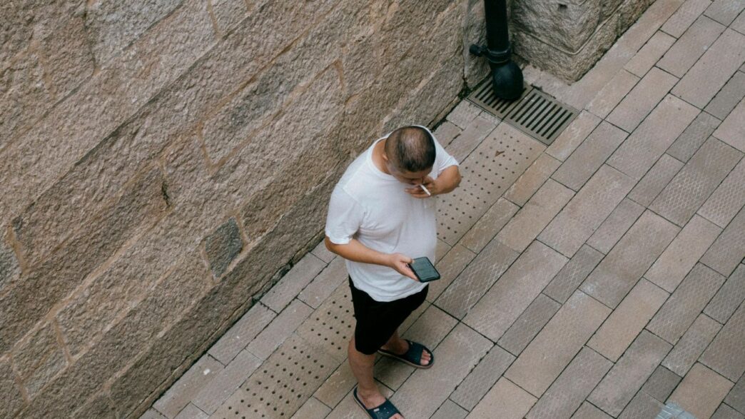 a man standing next to a wall talking on a cell phone