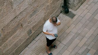 a man standing next to a wall talking on a cell phone