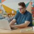 Man working on laptop at a colorful desk.