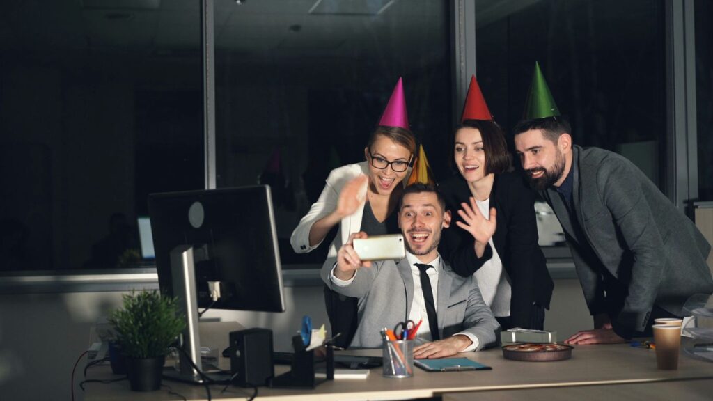 Colleagues celebrating with party hats taking a selfie.