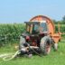 A tractor waters a field of crops.