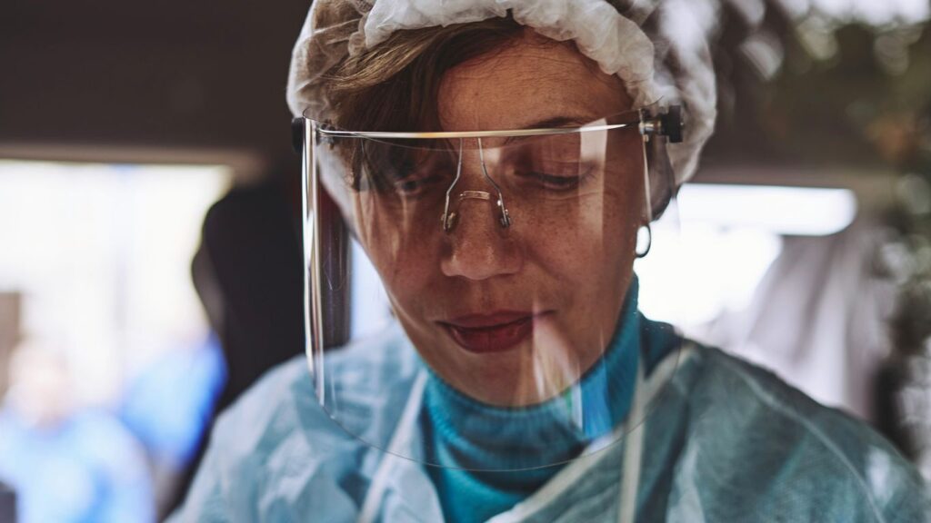 woman in teal scrub shirt wearing white head band