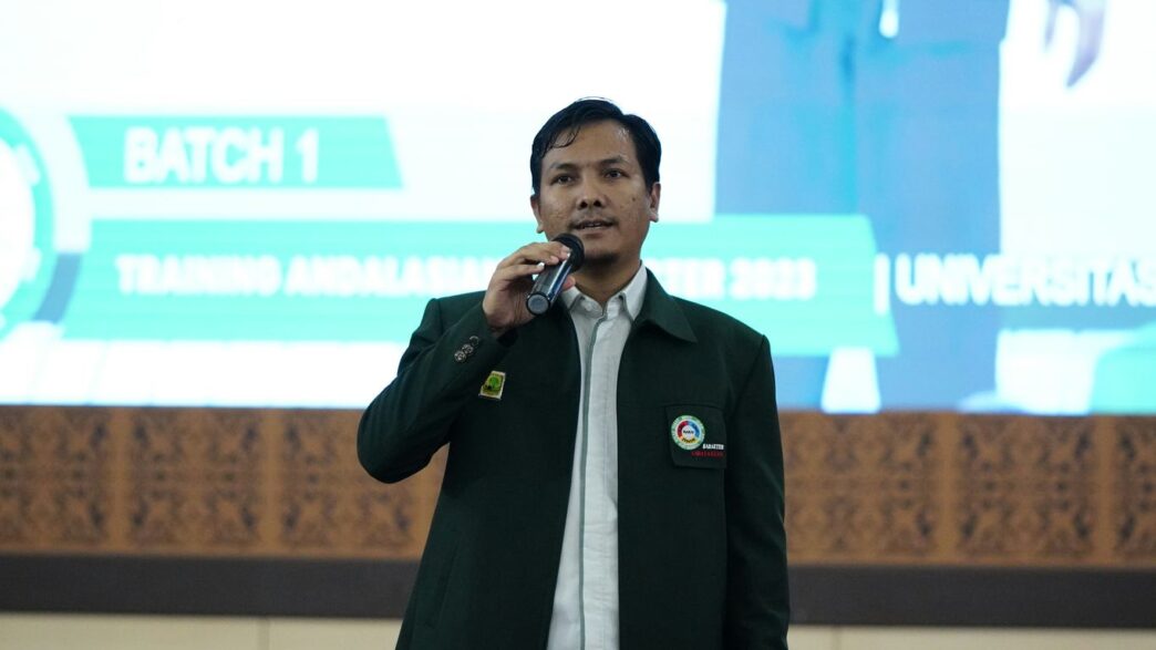 a man standing in front of a screen talking on a cell phone