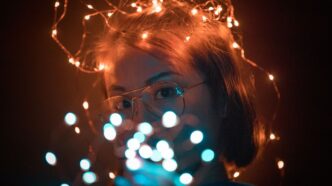 woman wearing brown framed eyeglasses with string lights on her head