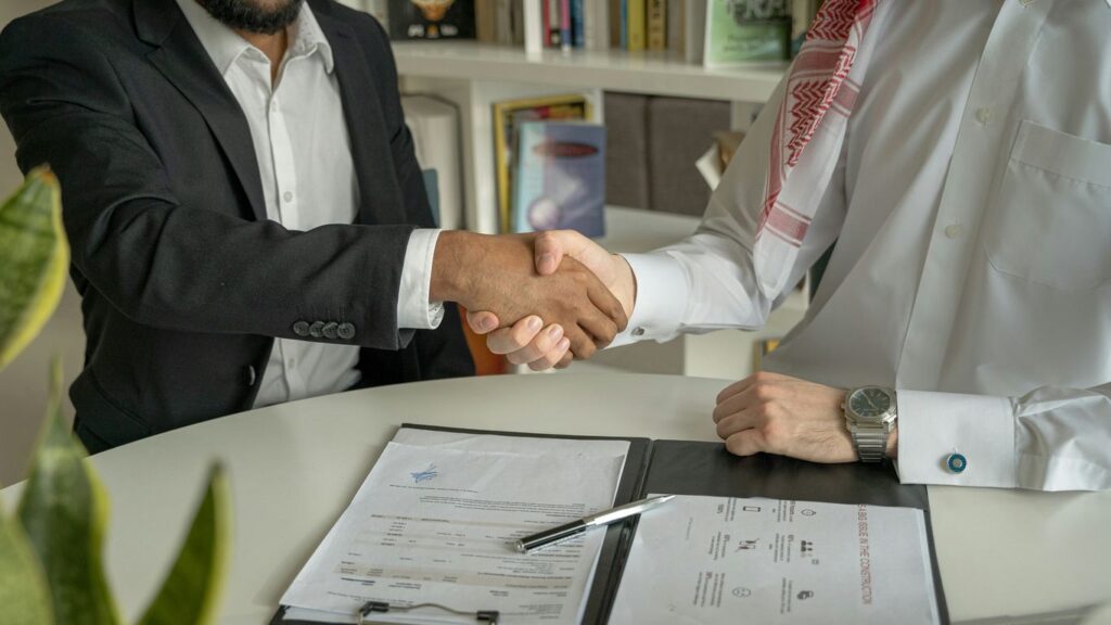 a couple of men shaking hands over a desk