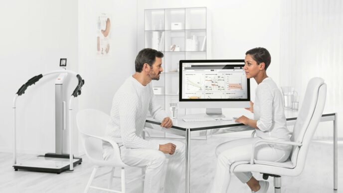 man in white dress shirt sitting on white chair in front of computer