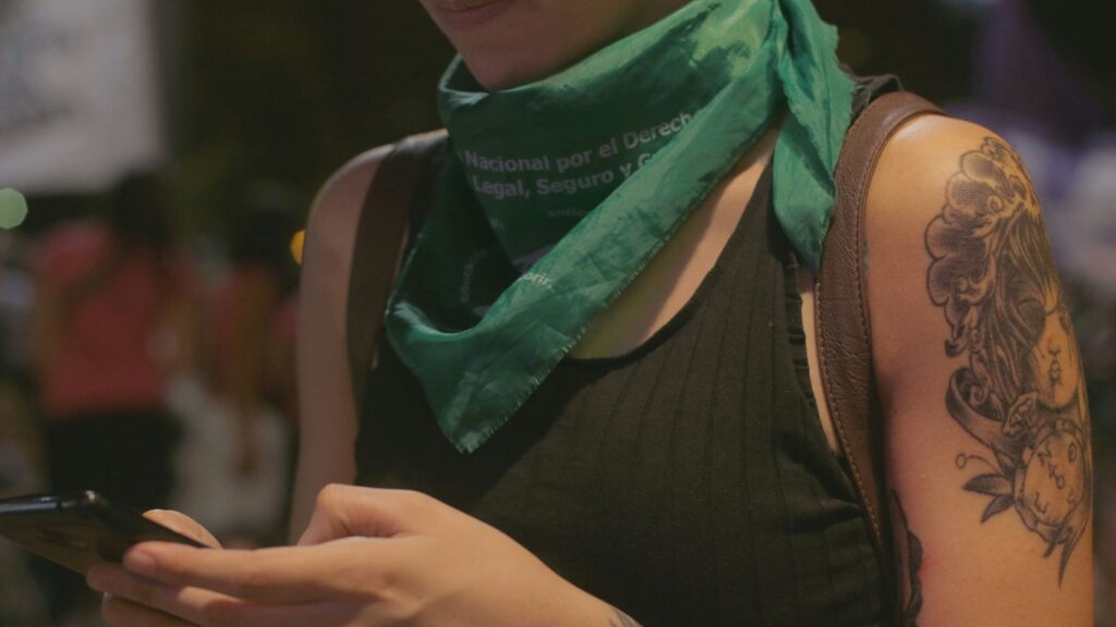 person wearing black tank top holding smartphone