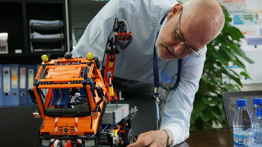 A man looking at a lego robot on a table