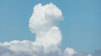 A plane flying through a cloud filled sky