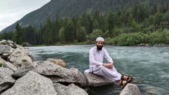 a man sitting on a rock in the middle of a river