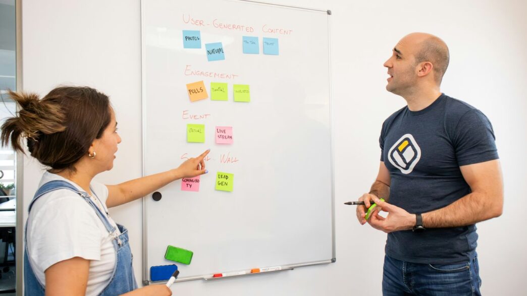 a man and a woman standing in front of a white board