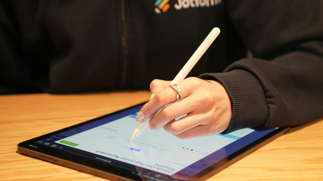 a person writing on a tablet with a pen