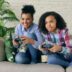 Two women playing video games on a couch.