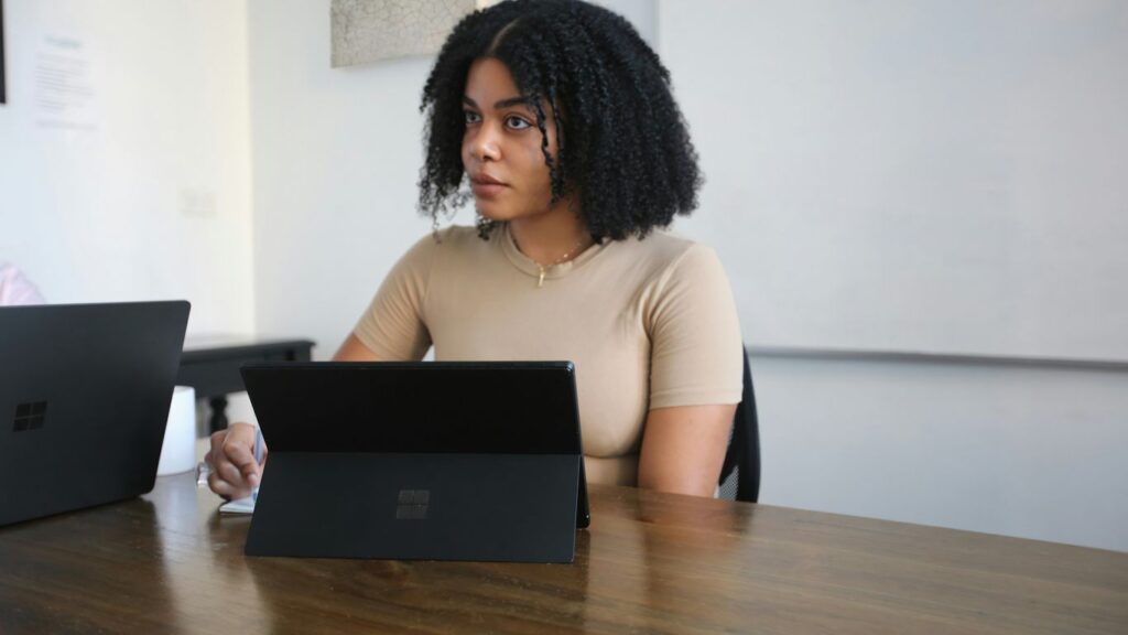 Female worker sitting in a board room with black Surface laptop on the table