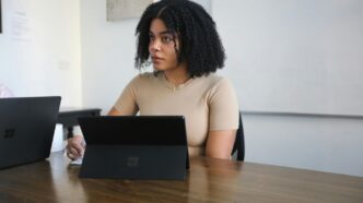 Female worker sitting in a board room with black Surface laptop on the table