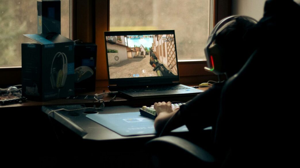 A gamer plays a video game on their laptop.