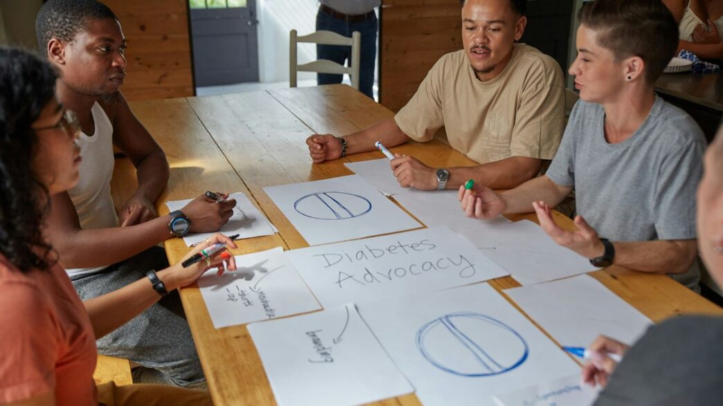 People collaborate on diabetes advocacy designs at a table.