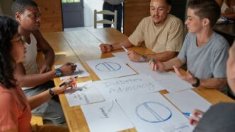 People collaborate on diabetes advocacy designs at a table.