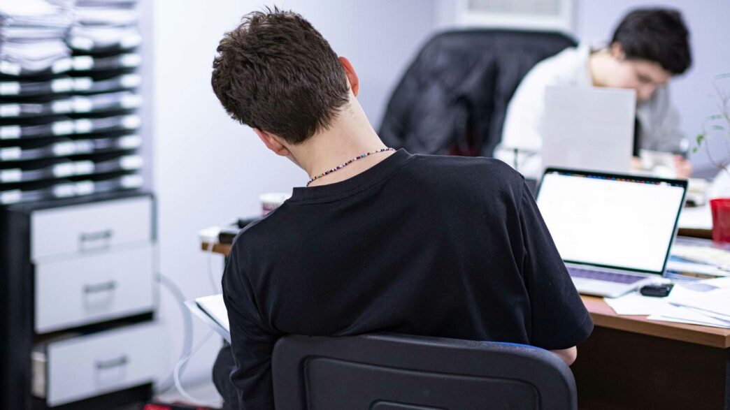 a man sitting at a desk in front of a laptop computer