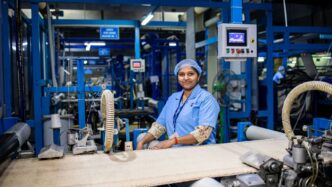 Factory worker smiles while operating machinery.