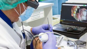 a person in a mask and gloves using a laptop