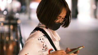 a woman wearing a face mask looking at her cell phone