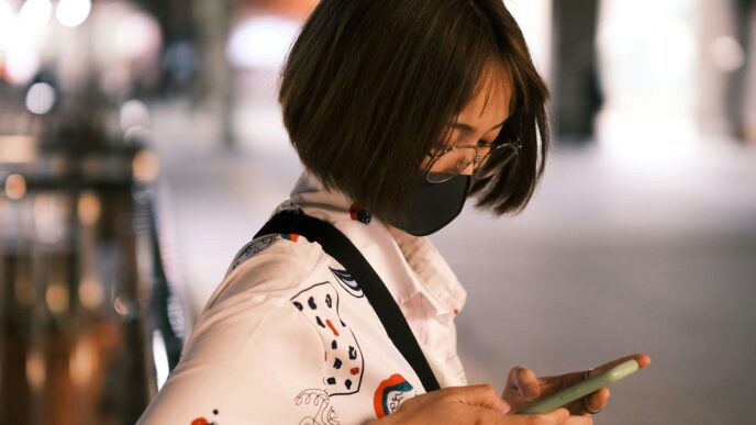 a woman wearing a face mask looking at her cell phone